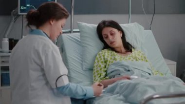 Doktor pratisyen hasta belirtilerini panoya yazıp nabzını kontrol ediyor.