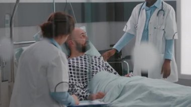 Hasta, hastalık tedavisi sırasında yatakta yatarken doktorlarla konuşuyor.