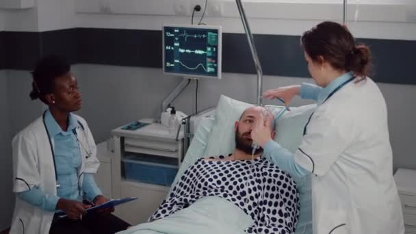 Equipo médico monitoreando los latidos cardíacos del hombre enfermo durante la cita respiratoria — Vídeo de stock