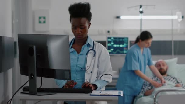 コンピュータに医療専門知識を入力するアフリカ系アメリカ人医師の正面図 — ストック動画