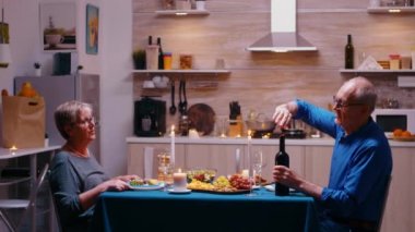 Yaşlı adam şarap şişesini açıyor.