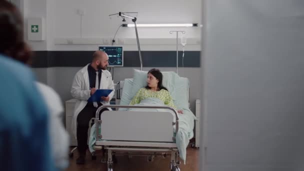Widok z przodu chorej kobiety odpoczywającej w łóżku dyskutującej z onkologiem lekarzem — Wideo stockowe