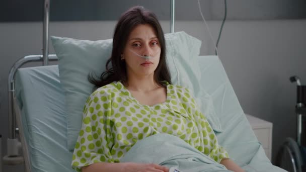 Пацієнт, який носить носову кисневу трубку, дивиться в камеру — стокове відео