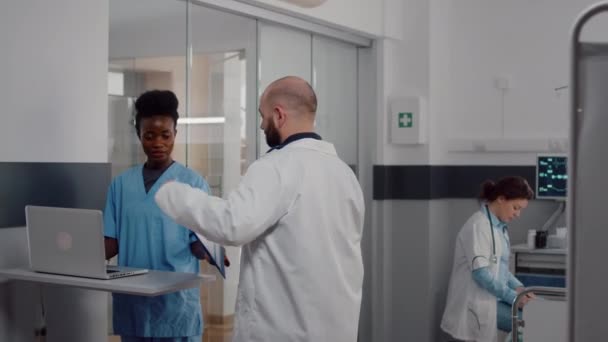 Enfermera practicante en uniforme médico escribiendo tratamiento de recuperación en el ordenador portátil — Vídeo de stock