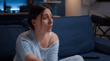 Duyarlı kadın TV 'de drama filmi seyrediyor. Kanepede oturup ağlıyor.