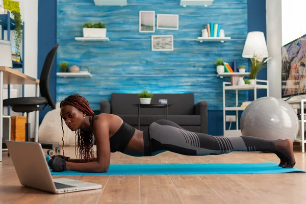 Atletica in forma donna nera in leggings seduto su yoga mat facendo posa tavola — Foto Stock