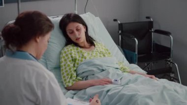 Doktor pratisyen hasta belirtilerini panoya yazıp nabzını kontrol ediyor.