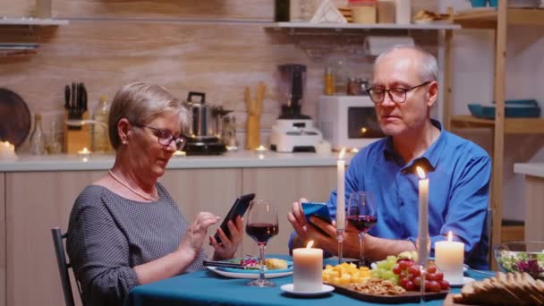 Pareja mayor usando teléfonos en la cocina — Vídeos de Stock