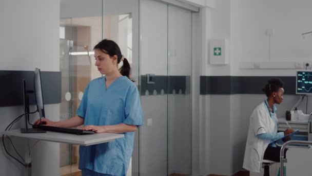 Вид спереду асистента, що вводить медичну експертизу на комп'ютері — стокове відео