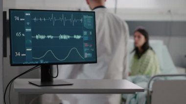 Hasta kadın yatakta dinleniyor. Uzman doktor hastalığının belirtileriyle tartışıyorlar.