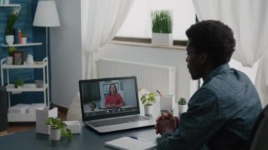 Afrika kökenli Amerikalı uzaktan çalışan bir işçi ortakları ve iş arkadaşlarıyla internet üzerinden iş görüşmesi yapıyor.
