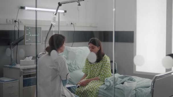 Beteg nő beszél az orvosokkal, miközben az ágyon ül a betegség gyógyulása alatt. — Stock videók