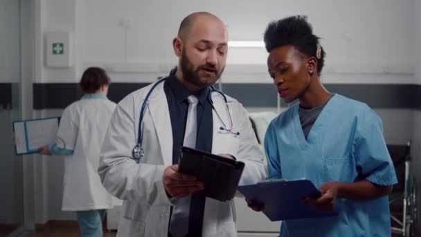 Medicul practician cu asistent negru de verificare a tratamentului de recuperare — Videoclip de stoc