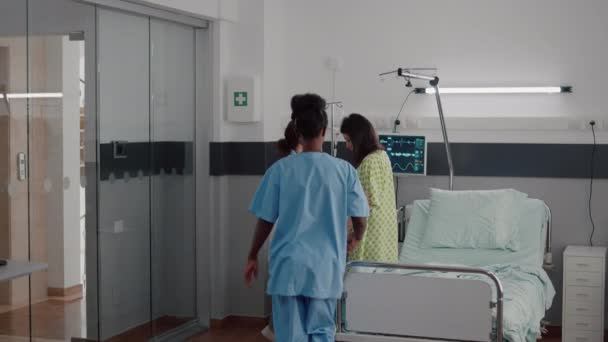 Enfermera afroamericana con médico ayudando al paciente a levantarse de la cama — Vídeos de Stock