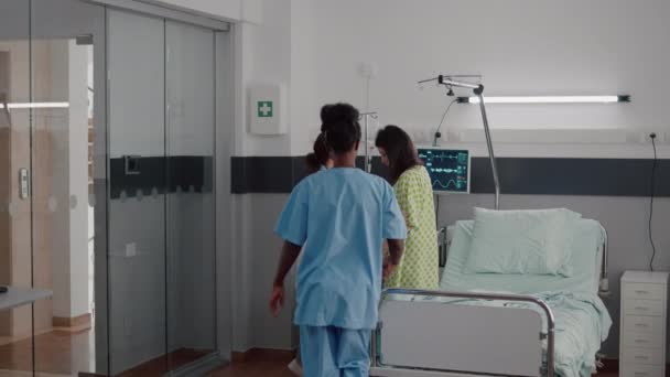 Afro american nurse with doctor helping patient to stand up from bed — Stock Video