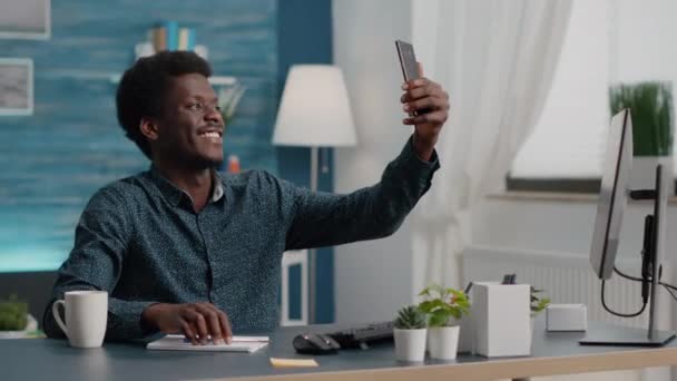 Otantik, mutlu, Afrikalı Amerikalı bir adam sosyal medyada paylaşmak için oturma odasında selfie çekiyor. — Stok video