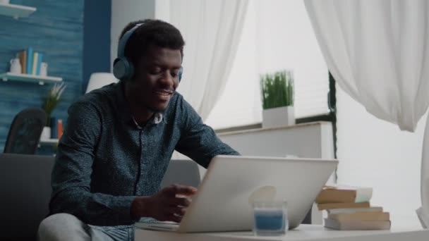 Negro africano americano hombre usando auriculares, escribiendo en el ordenador portátil — Vídeos de Stock