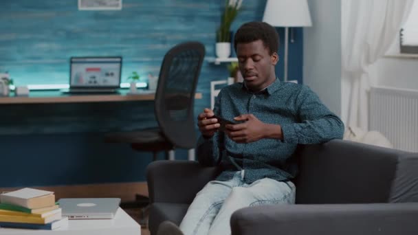 Uitgeputte Afro-Amerikaanse man die in slaap valt terwijl hij de telefoon in zijn handen houdt — Stockvideo