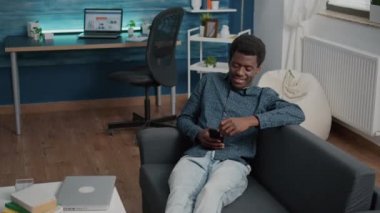 Elinde telefon olan Afrikalı Amerikalı adam online yayın hizmetlerinin içeriğine bakıyor.