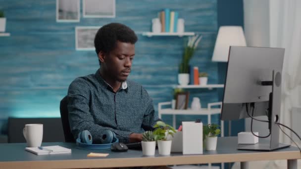 非裔美国人的黑人经理在总部电脑上工作时，用耳机听音乐 — 图库视频影像