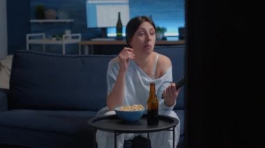 Uzaktan kumanda kullanan, televizyon kanallarını değiştiren, komik filmler arayan bir kadın.