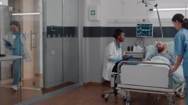 Afro-Amerikalı pratisyen, hastalığın semptomlarını analiz eden hasta adamı izliyor.