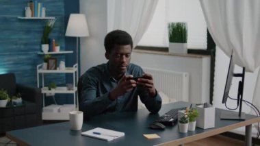 Neşeli mutlu siyah adam telefonunda video oyunları oynuyor.