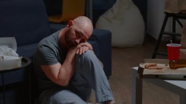 Üzgün, umutsuz, üzgün, yerde oturmuş yalnızlık hisseden bir adam.