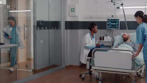 Afro amerikan utövare övervakar sjuk man analysera sjukdomssymptom — Stockvideo