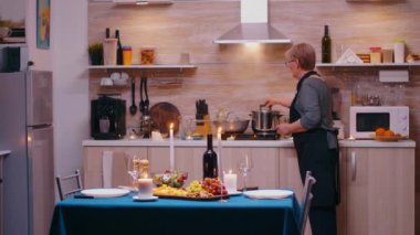 Yaşlı kadın koca için yemek pişiriyor.