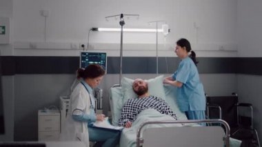 Pratisyen doktor hasta bir adamı panoya hastalık tedavisi yazarken izliyor.