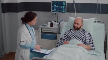 Hasta adam yatakta dinleniyor. Oksijen tüpü takıyor. Hastalık belirtilerini açıklıyor.