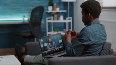 İnternet konferansında iş arkadaşlarıyla sohbet etmek için bilgisayarı açan siyahi bir adam.