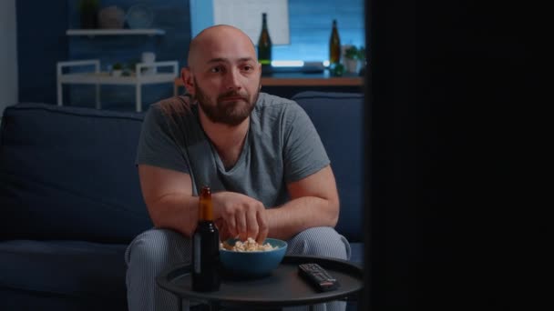 Pria ketakutan menonton film horor di TV makan popcorn duduk di sofa — Stok Video