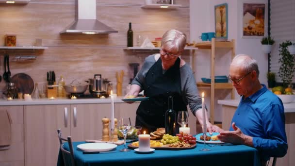 Oudere gepensioneerde vrouw serveert diner — Stockvideo