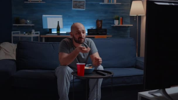 Relax muž tráví volný čas koukáním na televizi jíst popcorn — Stock video