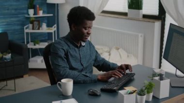 Otantik gülümseyen siyah Afrikalı Amerikalı adam evde çalışıyor.