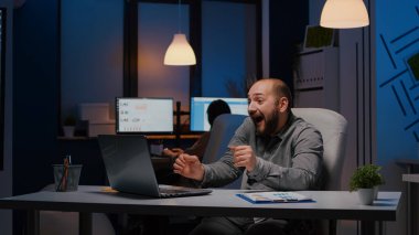 Mutlu başarılı iş adamı dizüstü bilgisayara bakarken gülümsüyor