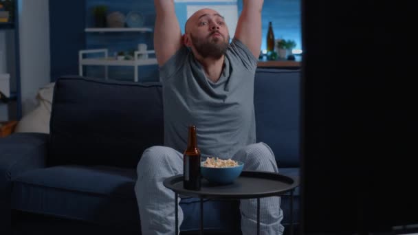 Man håller fjärrkontroll äta popcorn titta på sport på TV — Stockvideo