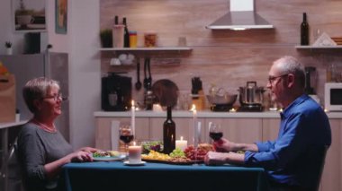 Yaşlı çift bir kadeh şarap içiyor.