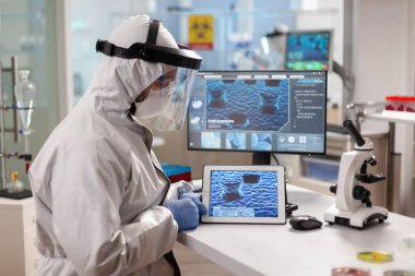 Pet suit giyen laboratuvar kimyageri tablet bilgisayar kullanıyor.