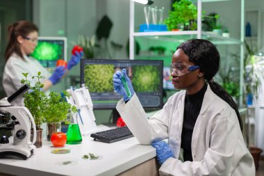 Biyolog kadın, yeşil DNA örneğini inceleyen genetik sıvıyla tüp tutuyor.