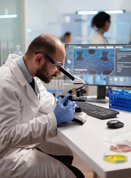 Médico químico mirando a través del microscopio en la muestra de virus —  Fotos de Stock