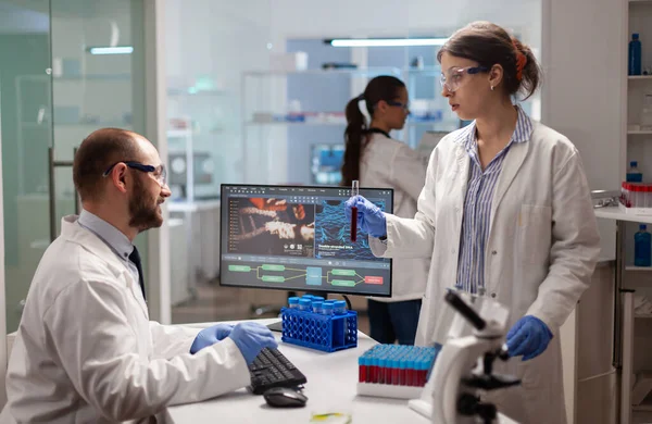 Medical chemists disscussing about vaccine development holding test tube with blood sample. — Stock Photo, Image