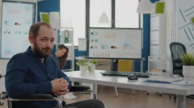 Genç engelli adam projesi yöneticisi kameraya bakıyor