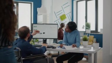 Siyahi yönetici kadın felçli takım lideriyle konuşuyor grafikleri kontrol ediyor