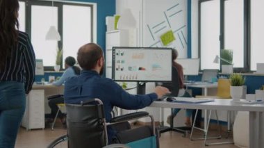 Tekerlekli sandalyede oturan engelli genç bir işçi istatistik verilerini analiz ediyor.