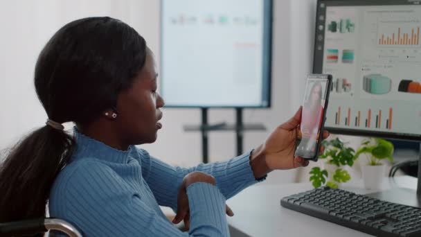 Afrikanska funktionshindrade arbetstagare som håller smartphone talar med avlägsen partner på videosamtal — Stockvideo