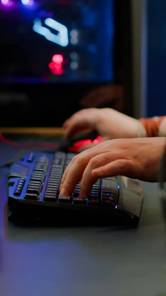 Fechar de digitação streamer no teclado RGB jogando videogame shooter espaço — Fotografia de Stock