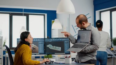 Adam proje yöneticisi dizüstü bilgisayar tutuyor ve ekranı işaret ediyor